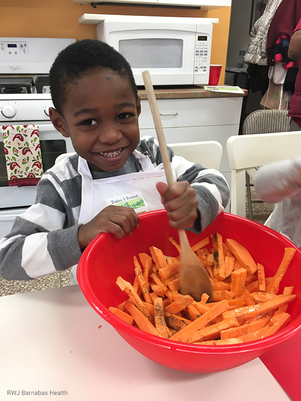 A young boy mixes a bowl of carrots at a cooking class for children at Hannahs Kitchen inclusive facility