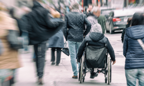 Person in a wheelchair on a crowded sidewalk
