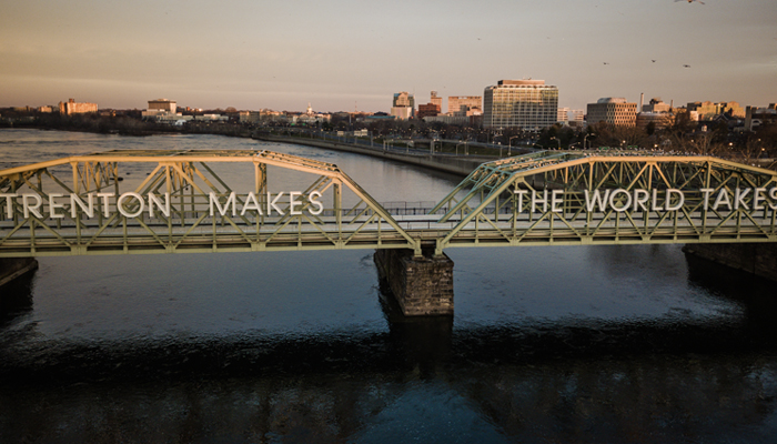 A bridge across the Delaware River with a sign that says Trenton Makes, The World Takes
