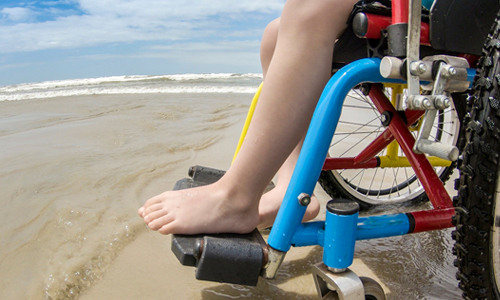 Person in an especially equipped wheelchair on a beach