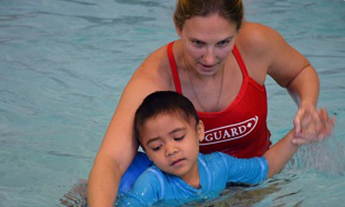 Lifeguard teaching child to swim
